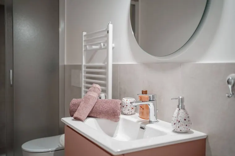 Trastevere Domus Iulia, Roma: il bagno con il mobile rosa cipria e lo specchio tondo